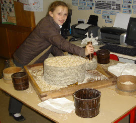 Using a Quern and sieve to fill a peck measure with flour
